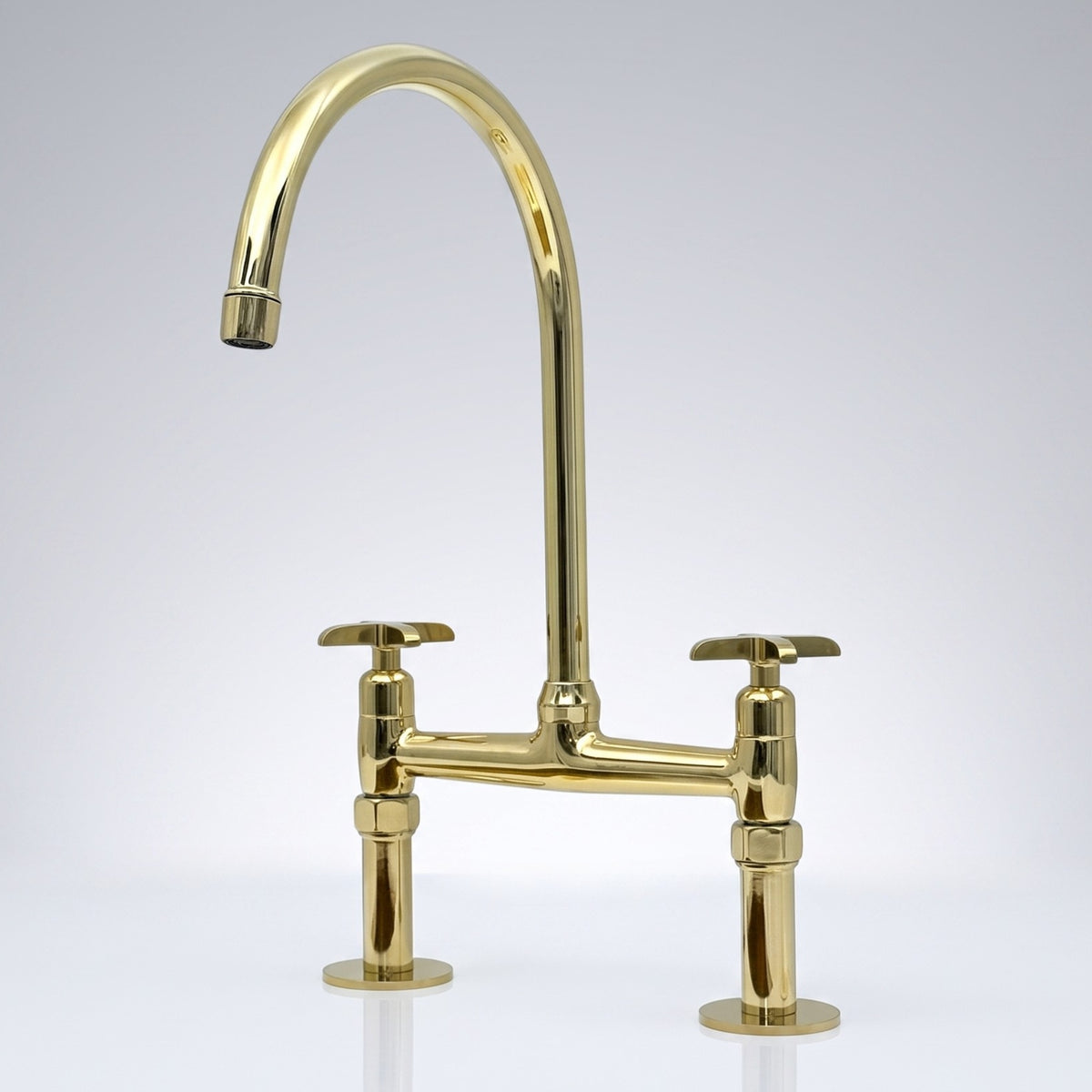 Unlacquered brass bridge kitchen faucet with cross handles shown in a kitchen setting